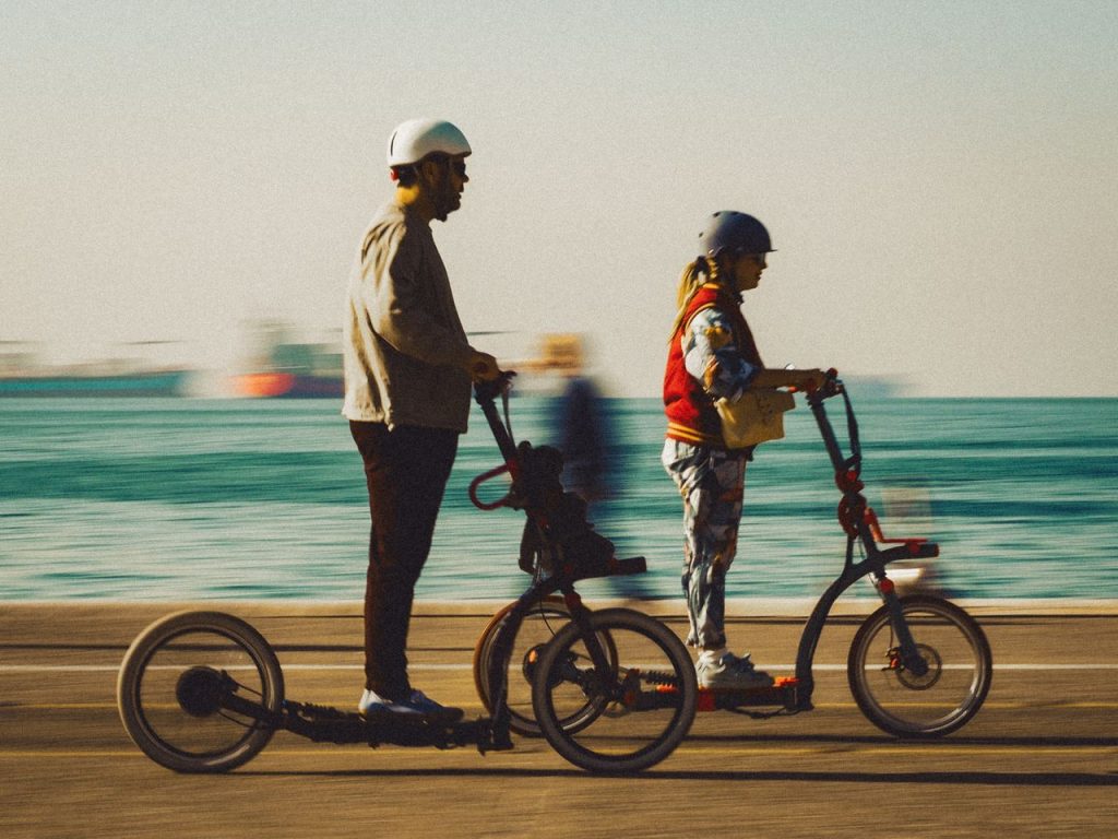 couple-riding-on-scooters-14139547 A man and woman enjoying a sunny day riding electric scooters along the seaside promenade.